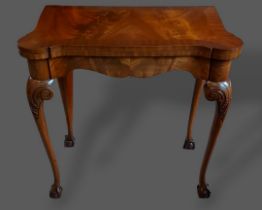 A mahogany card table, the crossbanded shaped hinged top raised upon carved cabriolet legs with claw