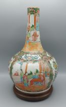 A Chinese Canton bottle neck vase, decorated with figure and bird amounst foliage, upon hardwood