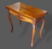 A Victorian walnut card table, the hinged top above a shaped carved frieze, raised upon cabriole