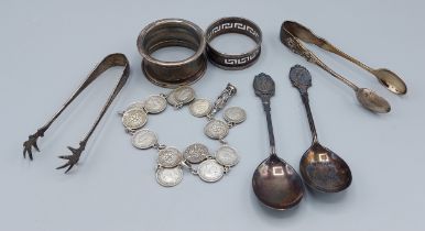 Two silver napkin rings together with two pairs of sugar tongs, a pair of silver spoons and a coin