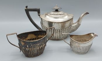 A George V silver three piece tea set of half lobed form, comprising of teapot, cream jug and