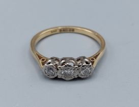 An 18ct gold three stone diamond ring, the three diamonds within a pierced setting, 2.7gms, ring