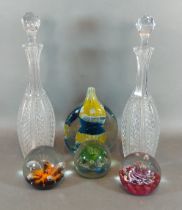 A pair of cut glass decanters with stoppers together with four glass paperweights