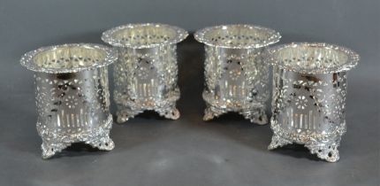 A set of four silver plated bottle stands of pierced from each with three low scroll feet, 12cms