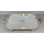 A 19th Century silver plated large two handled tray, with a central crest and four scroll feet,
