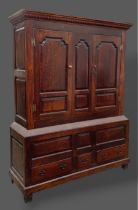 A george III oak Bacon cupboard, the moulded cornice above two panel doors, the lower section with