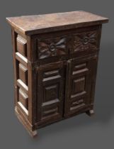 An early oak side cabinet, the thick plank top above a carved frieze drawer and two panel doors