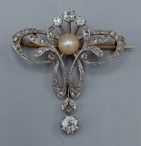 An Edwardian gold, diamond and pearl set brooch/pendant in the form of a bow with a central pearl