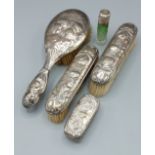 A silver backed four piece dressing table set comprising three brushes and a glass bottle, all