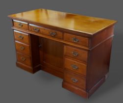 A late Victorian oak twin pedestal desk with nine drawers and brass handles with central cupboard,