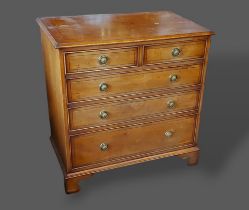 A 20th Century chest of two short and three long drawers with circular brass handles raised upon