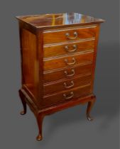 An Edwardian mahogany six drawer music chest with brass handles raised upon cabriole legs together