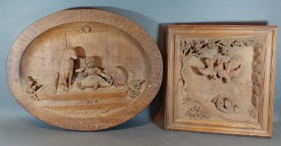 A Black Forest carved oval panel depicting a child with two dogs, 48cms X 62cms together with