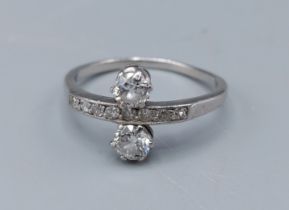 A two stone diamond ring, the two diamonds claw set flanking a band of smaller diamonds, 3.2gms,