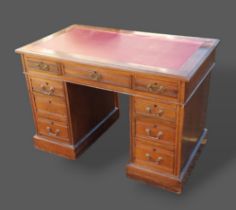 An Edwardian twin pedestal desk with nine drawers and brass handles upon plinth bases, 107cms