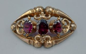 A Victorian brooch of pierced design and set with three Amethysts, 5.5cms long