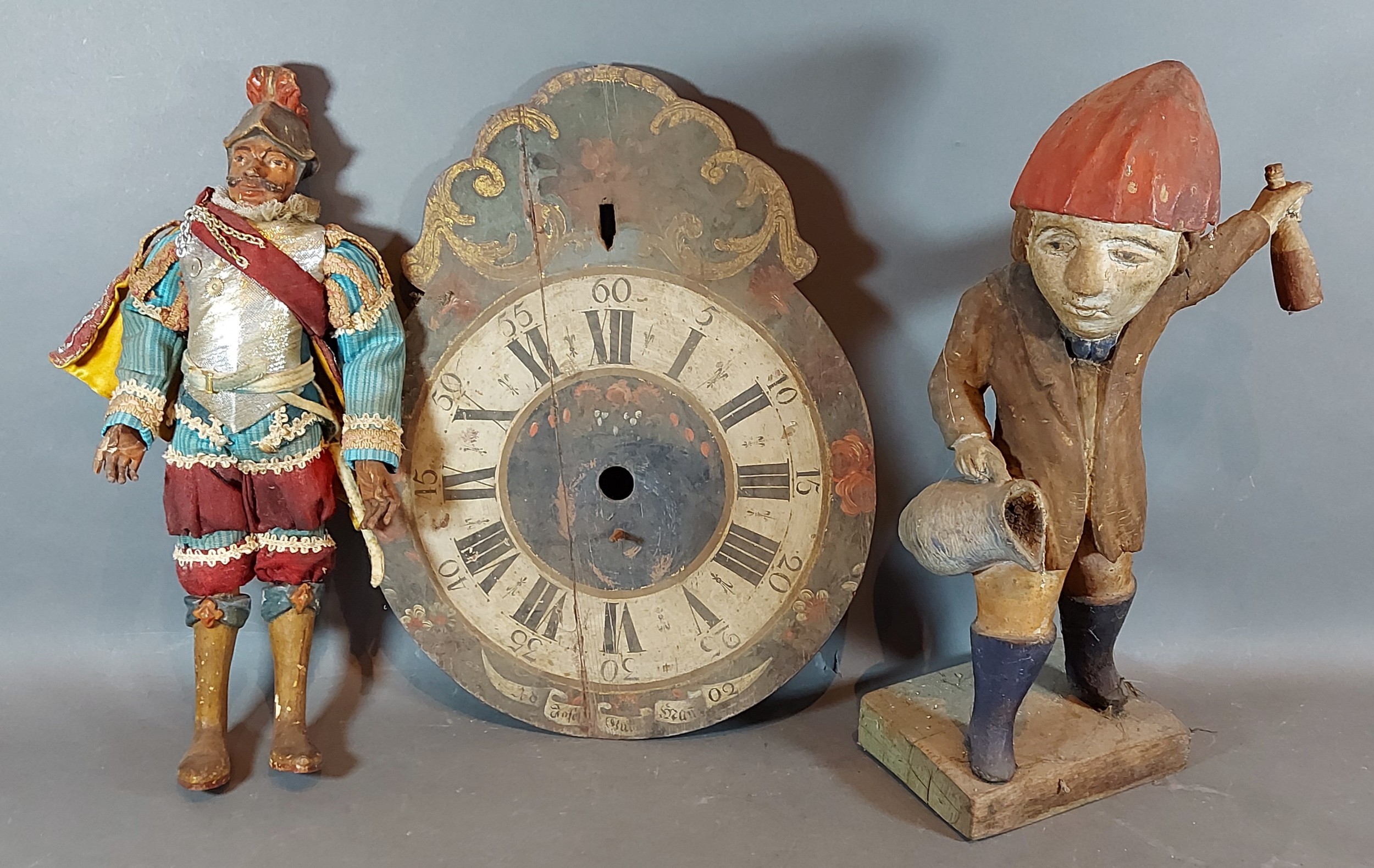 A Norwegian carved figure together with another figure and a clock face