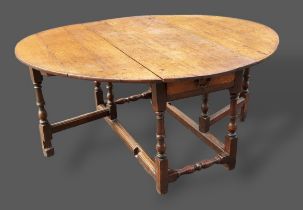 An 18th Century oak gateleg dining table with turned legs, 130cms x 148cms