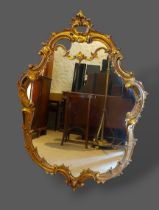A gilded wall mirror of shaped pierced and scroll form, 118cms X 87cms