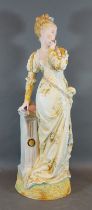 A large early 20th Century figure in the form a a lady in period dress standing by a pillar, 52cms