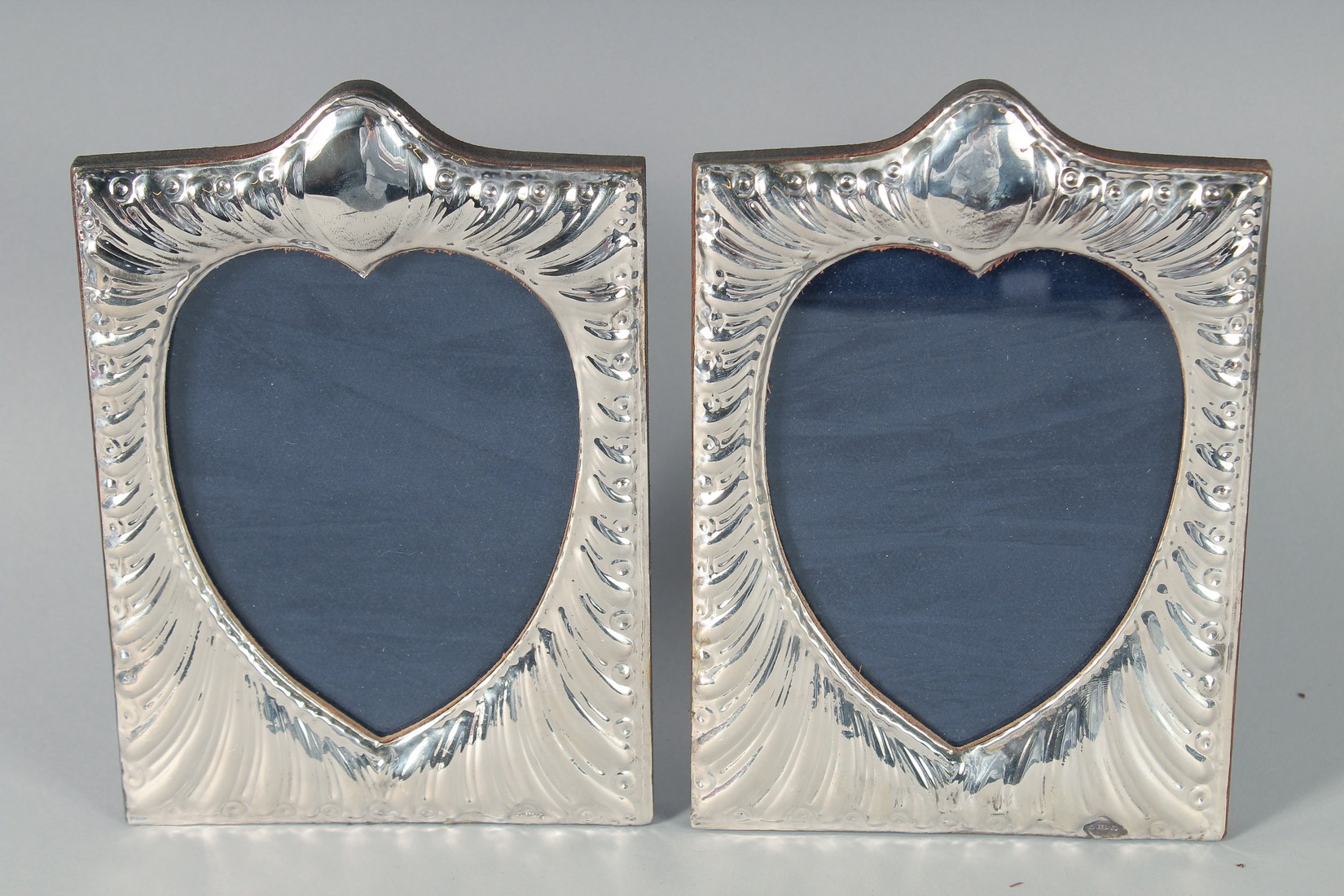 A PAIR OF SILVER HEAD SHAPED PHOTOGRAPH FRAMES, 18 cm x 12 cm.