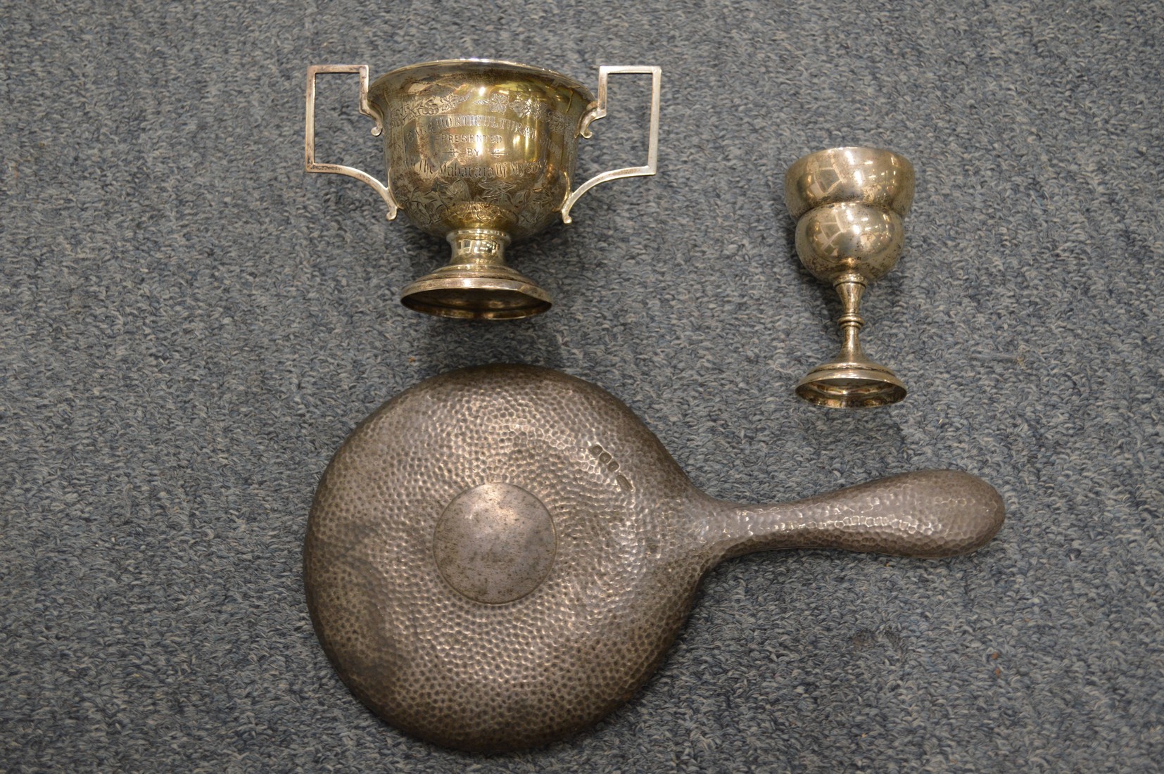 Silver backed dressing table mirror, a trophy cup and an egg cup.