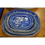 Four blue and white willow pattern plates.