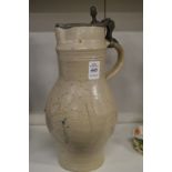 A large stoneware jug with pewter lid.