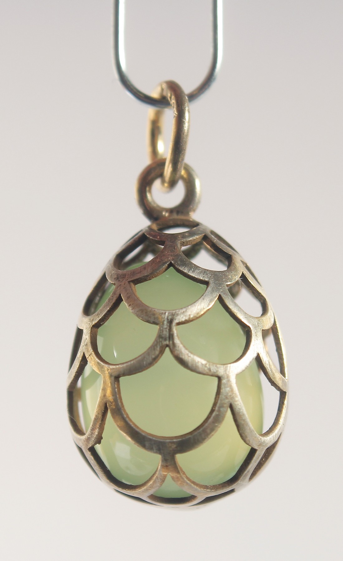 A SILVER AND JADE EGG SHAPED PENDANT, of cage design. 2cm high