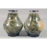 A PAIR OF ROYAL DOULTON STONEWARE GREEN FLORAL VASES. 7ins high.