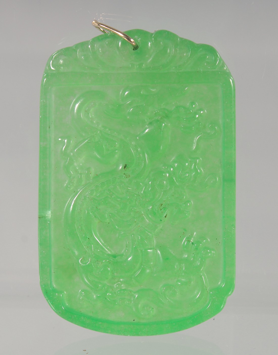 A CARVED GREEN JADE PENDANT with a gold suspension loop. 5.5cm high.