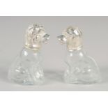 A PAIR OF NOVELTY GLASS AND SILVER-PLATED SALT AND PEPPERS, modelled as seated dogs.