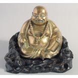 A CHINESE BRASS BUDDHA on a fitted carved and pierced hardwood base.