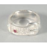 A SILVER OPAL AND RUBY BUCKLE RING.