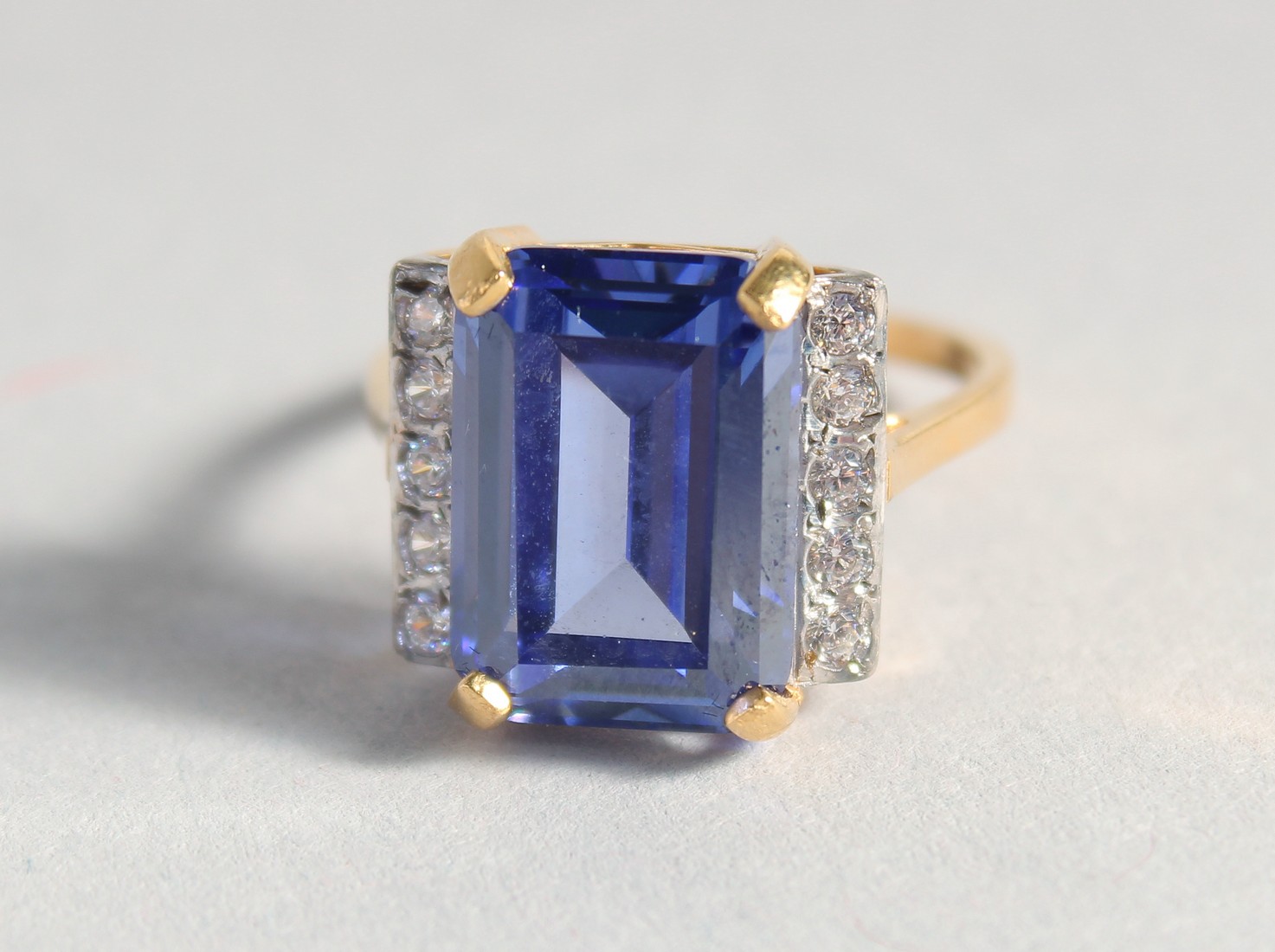 A SILVER GOLD-PLATED FAUX TANZANITE DECO STYLE RING.