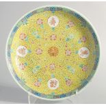 A LARGE CHINESE YELLOW GROUND FAMILLE ROSE PORCELAIN DISH, painted with longevity symbol and