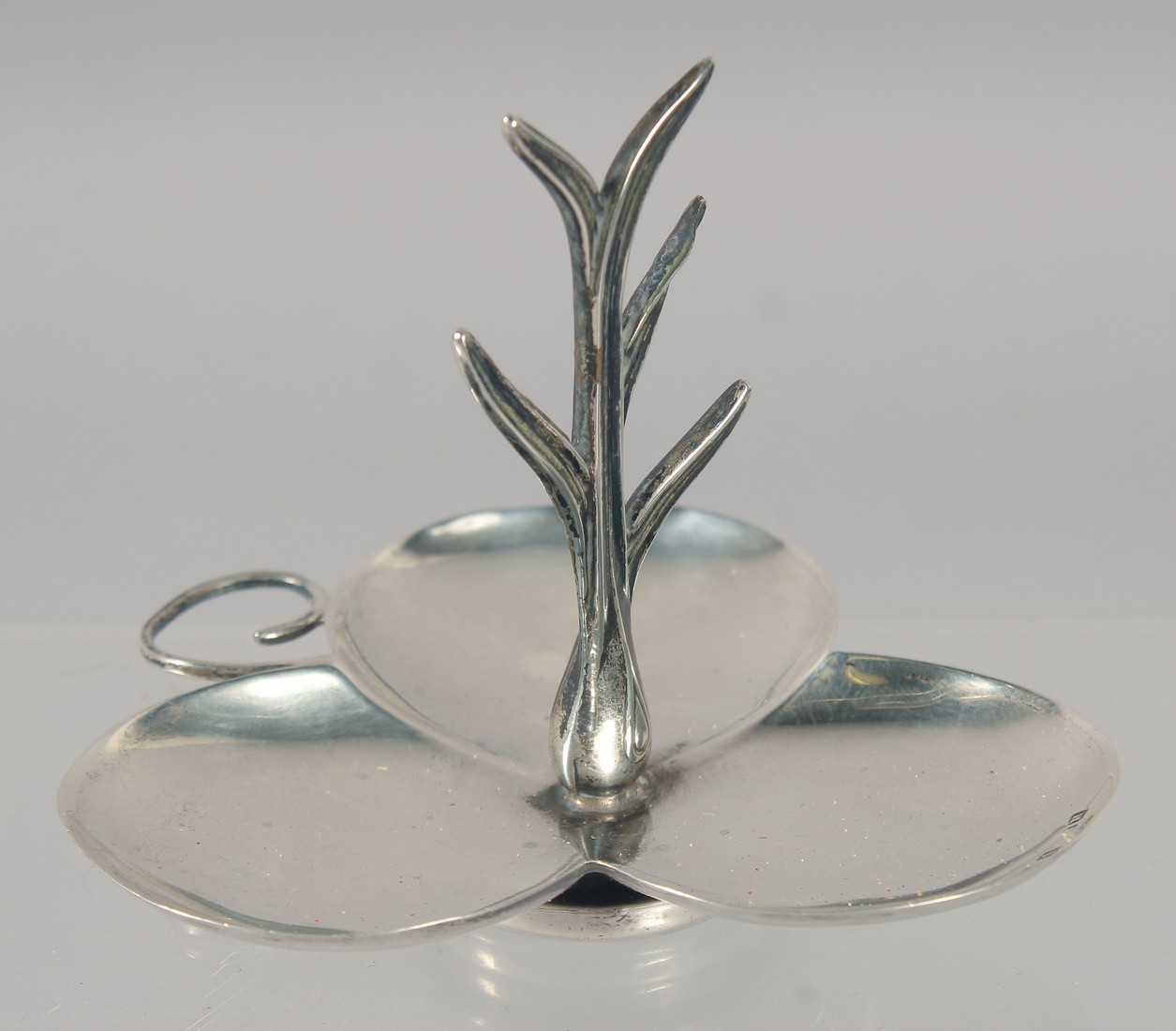 A SILVER COLOUR SHAPED RING STAND.
