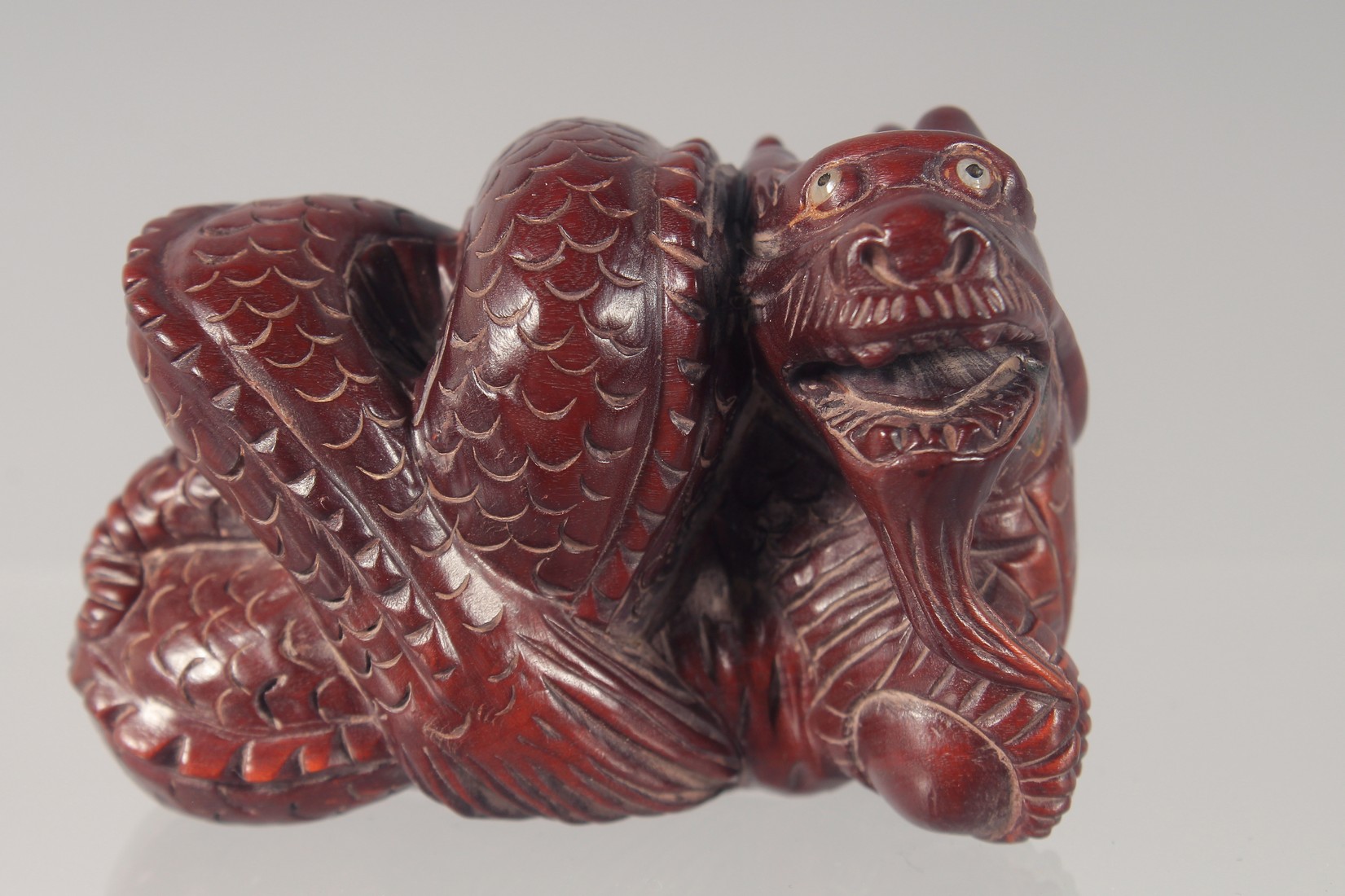 A CARVED WOOD NETSUKE modelled as a dragon 5.5cm long.