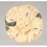 A JAPANESE BONE NETSUKE carved with faces. 4cm diameter.