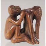 AN EROTIC CARVED WOOD NETSUKE modelled as a woman engaged in intercourse with a monkey.