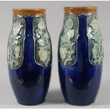 A PAIR OF ROYAL DOULTON STONEWARE BLUE FLORAL VASES. 9ins high.