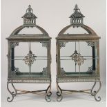 A PAIR OF ORNATE METAL LANTERNS on curving feet. 22ins high.
