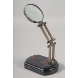 A SMALL BRASS MAGNIFYING GLASS on a stand.