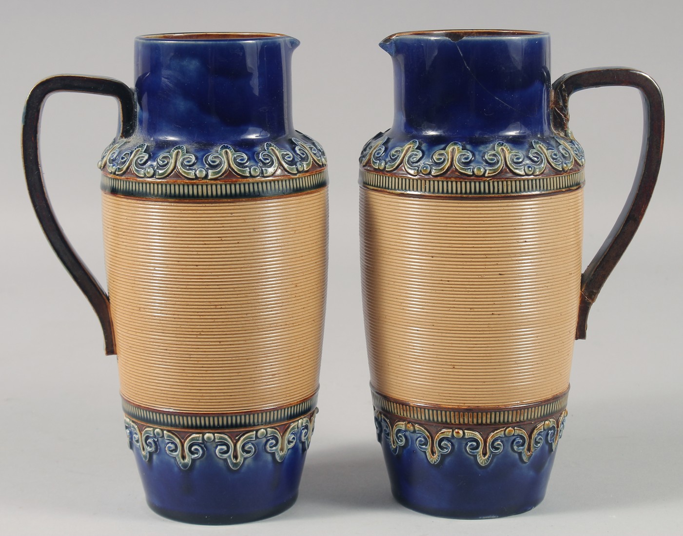 A PAIR OF ROYAL DOULTON STONEWARE JUGS with blue bands. 8ins high.