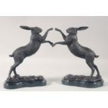 A PAIR OF CAST BRONZE "BOXING HARES" on marble bases. 11.5ins high.