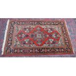 A GOOD PERSIAN CARPET, rust ground with vases of flowers and floral border. 7'2" x 4'5"