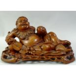 A LARGE CARVED HARDWOOD HOTEI, on a fitted carved hardwood stand, the figure reclining with a