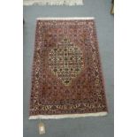 A good small Persian design rug, rust ground with stylised decoration 3'5" x 2'3".