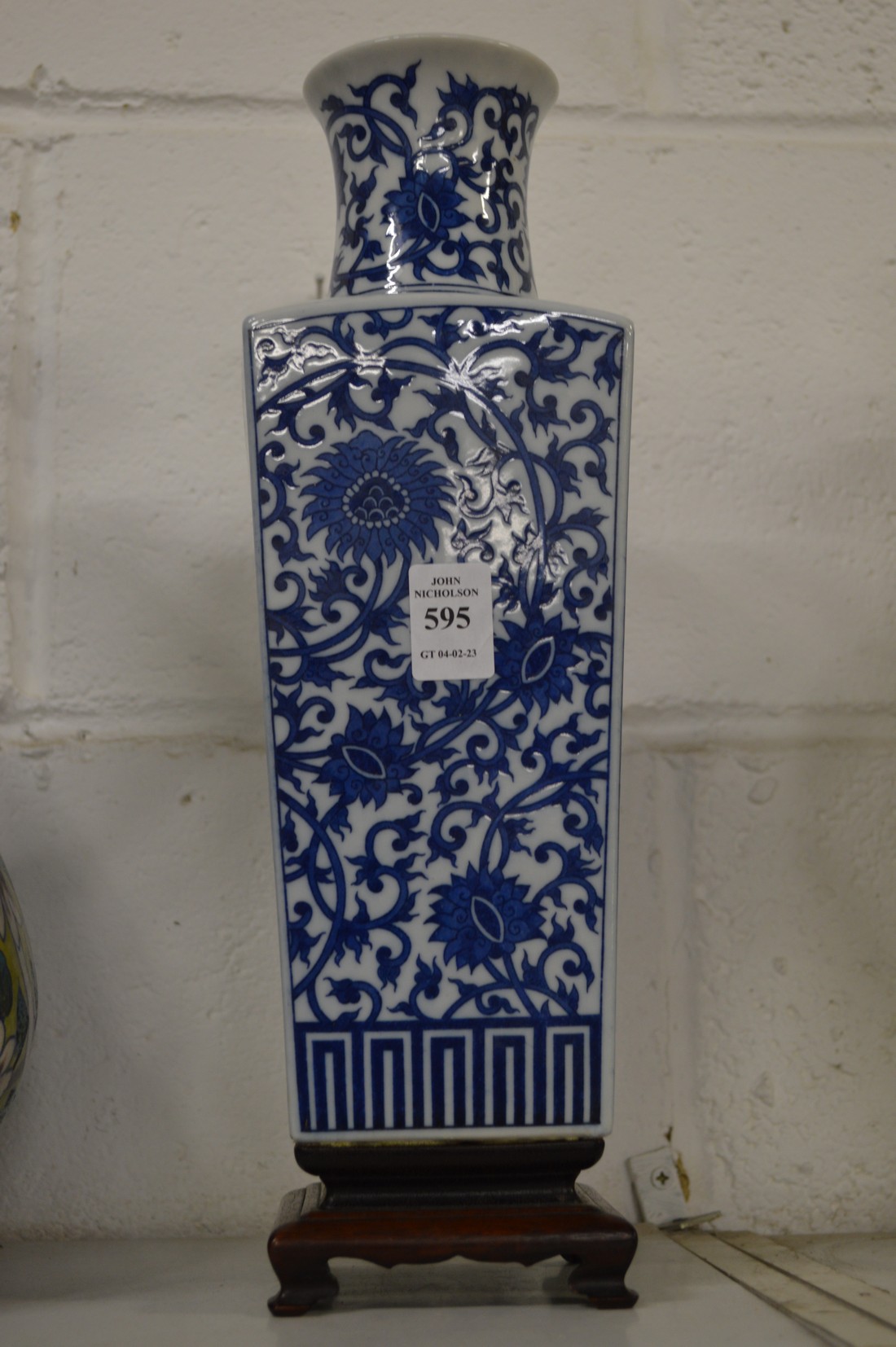A Chinese blue and white tapering square vase on hardwood stand.