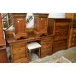 A modern hardwood bedroom suite comprising large chest of drawers, kneehole dressing table with